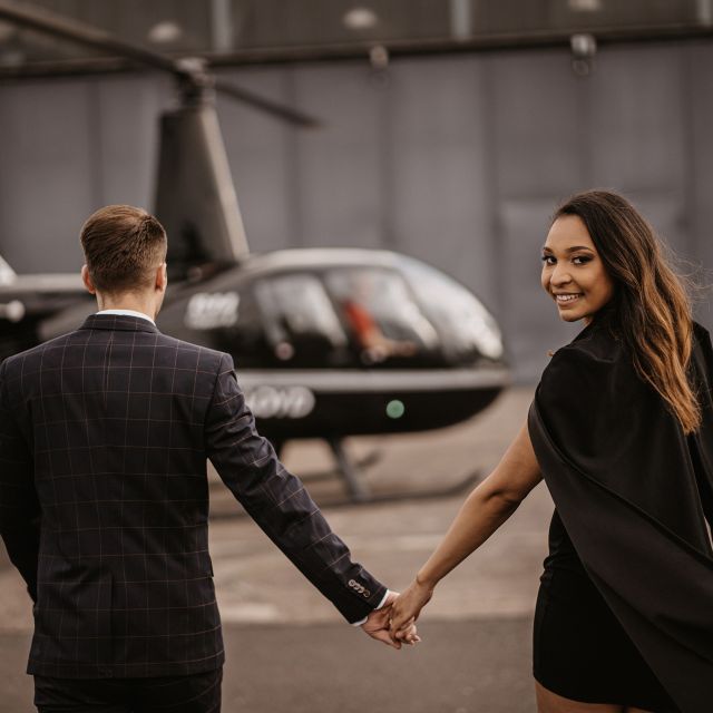 Ein Paar steht händchenhaltend vor einem schwarzen Air Lloyd Helikopter